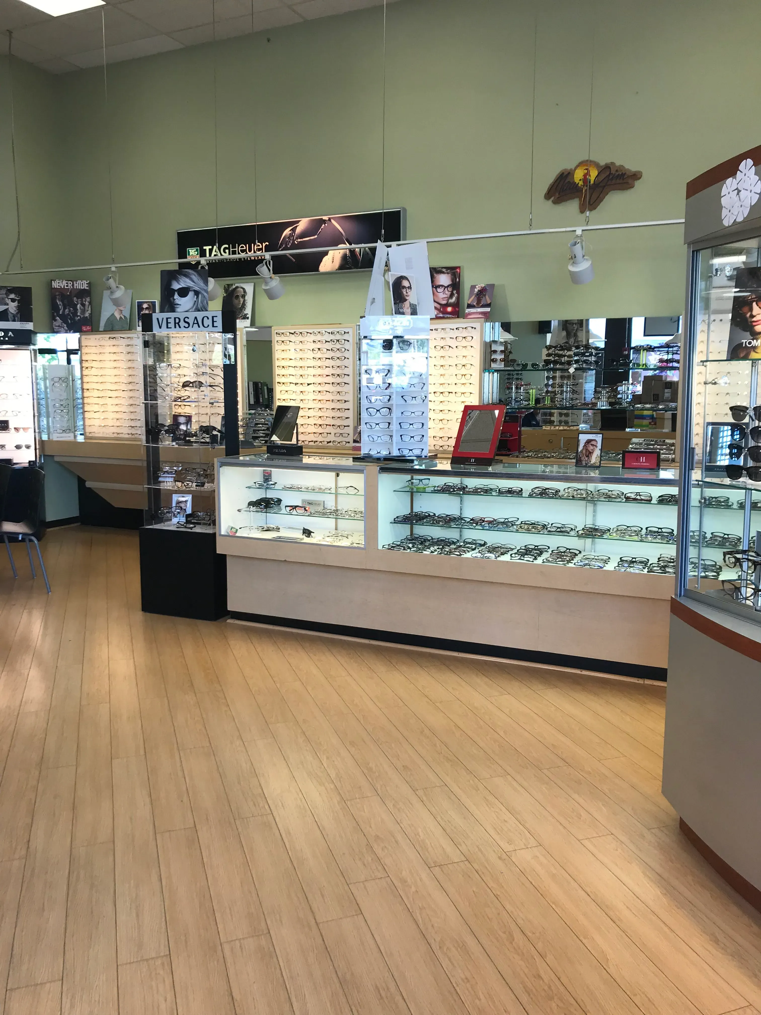 Interior of an eyewear store in Fremont, featuring a variety of glasses displayed on shelves with brands like Versace and Tag Heuer. The store has wood flooring and showcases multiple eyewear options.